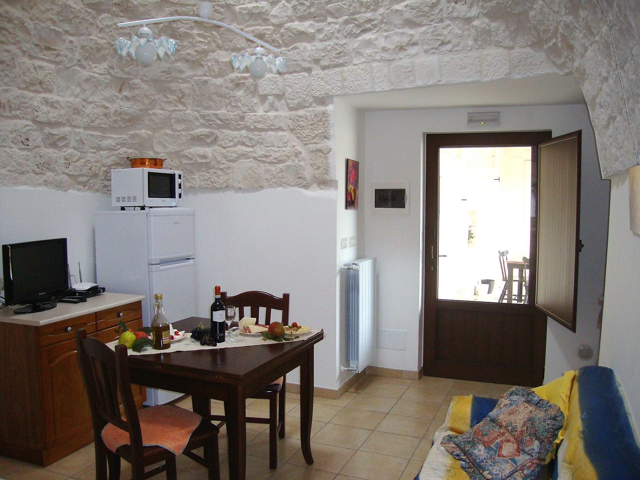Soggiorno con angolo cottura sotto la volta in pietra, Trullo Il Nido