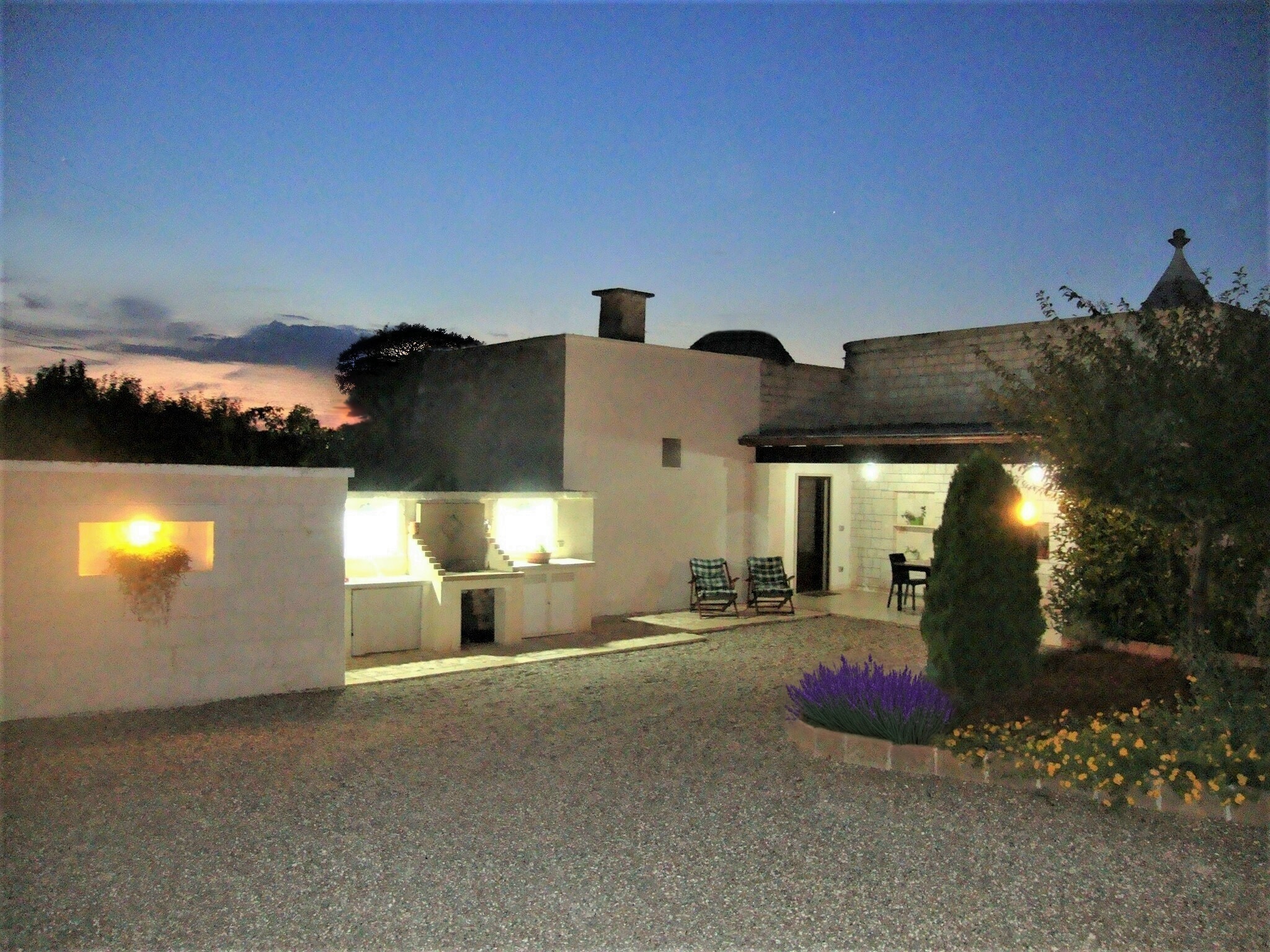 Piazzale del Trullo Il Nido al tramonto con cucina esterna illuminata