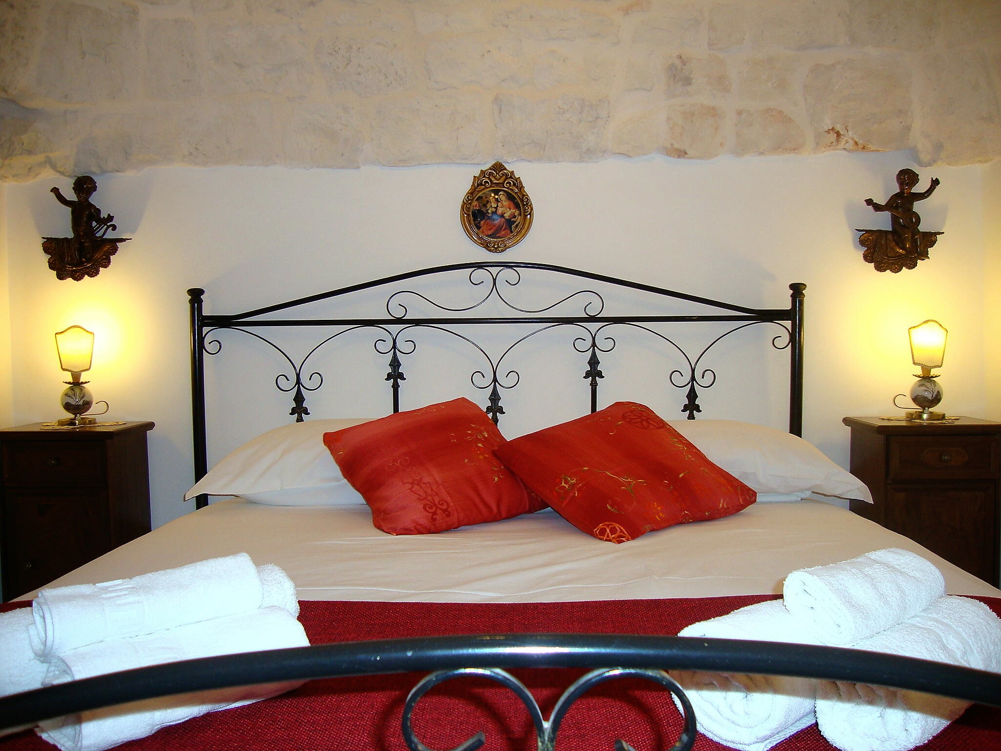 Camera da letto del Trullo Incanto con testiera in ferro battuto e parete in pietra a vista