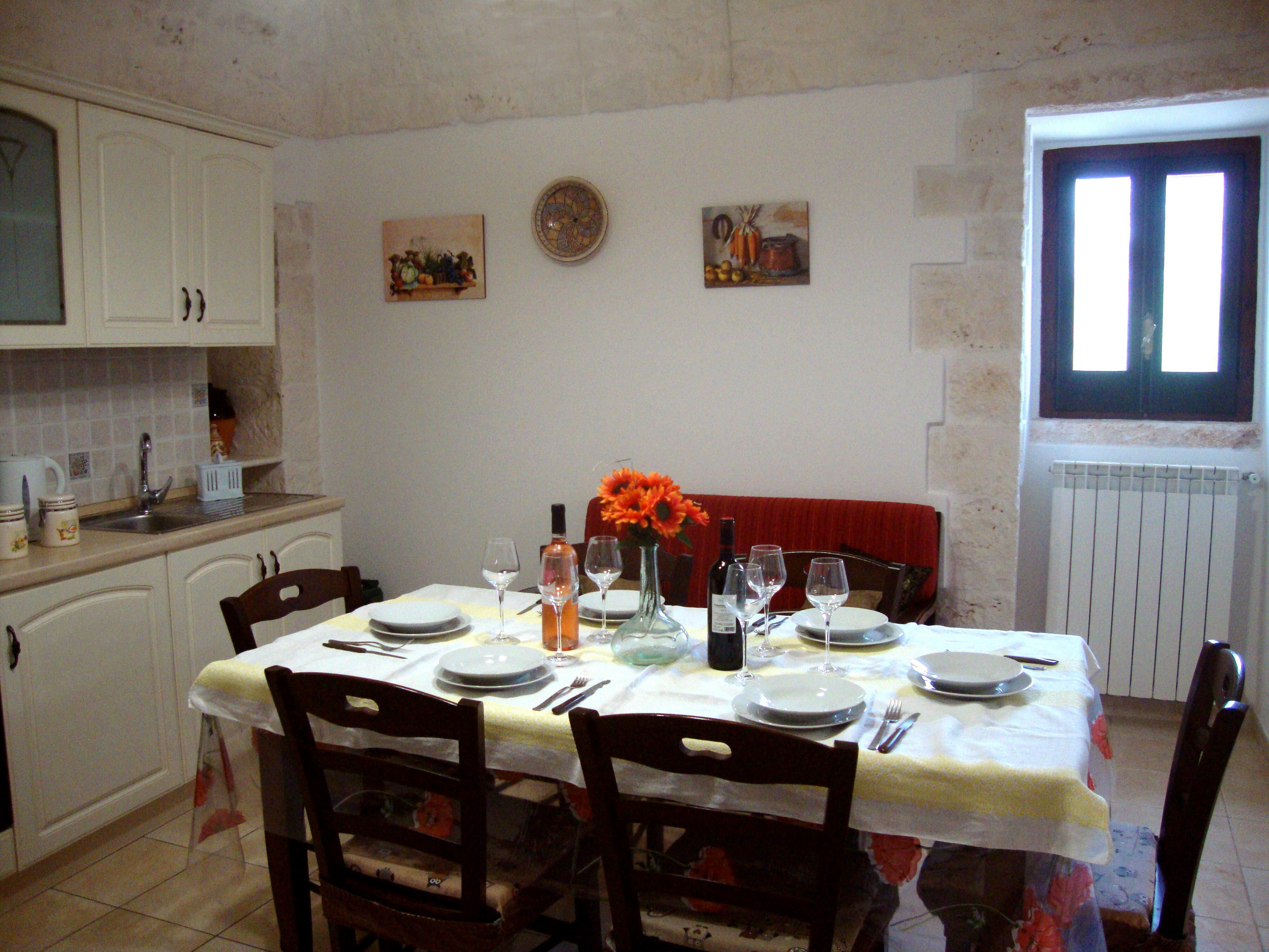 Cucina abitabile del Trullo Incanto con tavolo apparecchiato per 6 persone